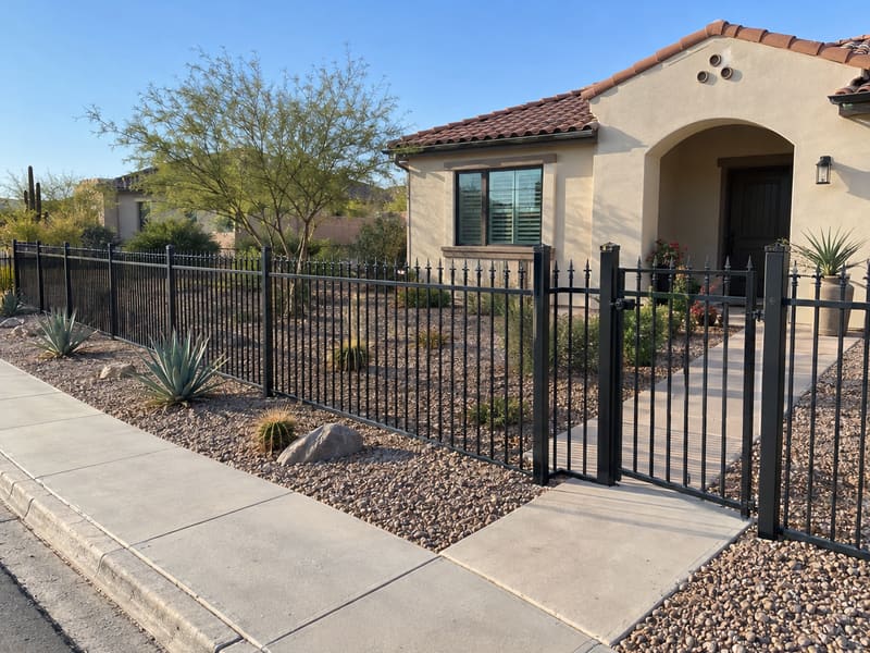 Black ornamental fence and gate around a desert front yard